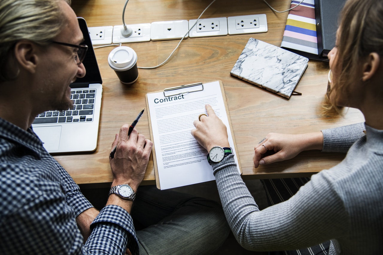 Two people at workspace reviewing engineering recruiting contract.